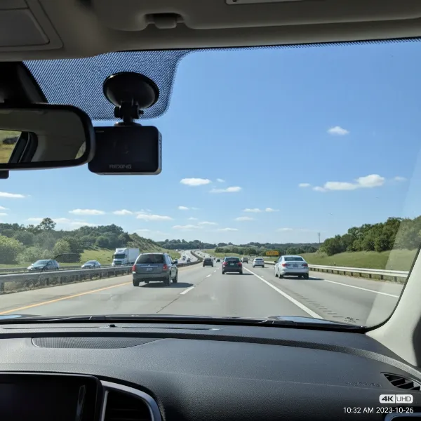 A Rexing V1 4K dash cam mounted discreetly on a car windshield, showing a clear view of the road ahead with sharp detail.